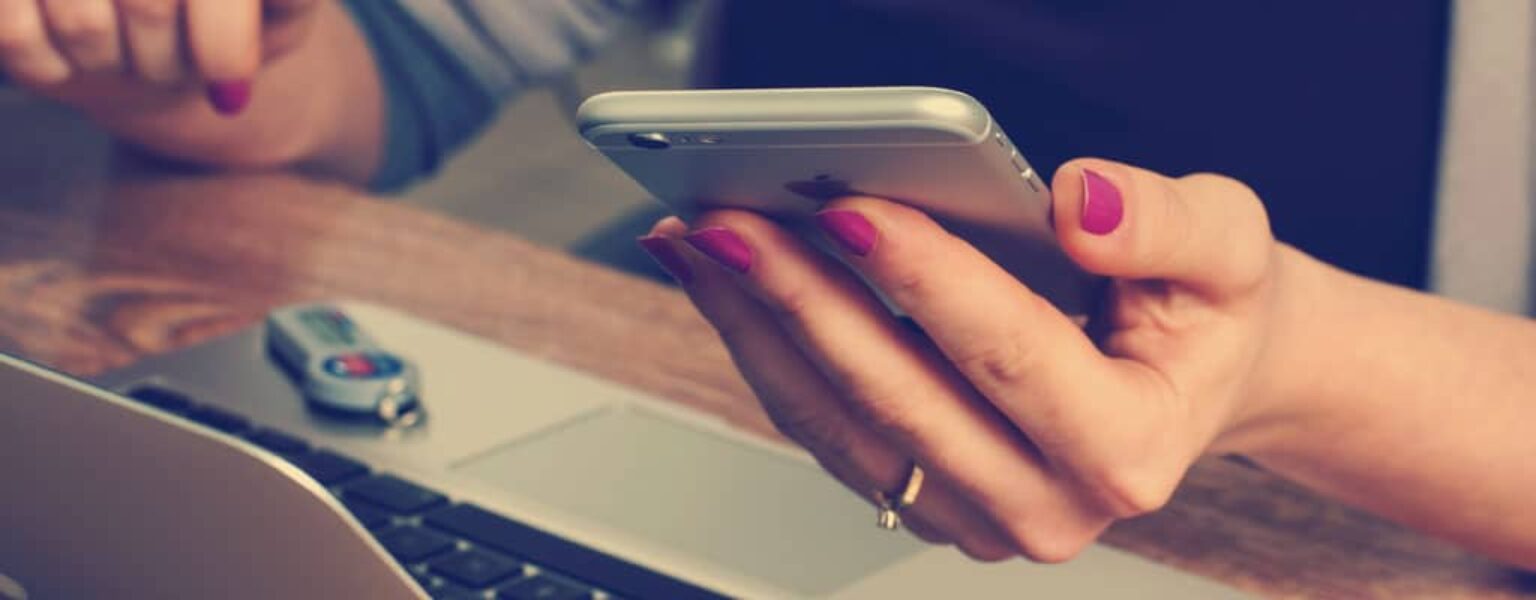 Importance of Two Factor Authentication Woman logging into her computer using two factor authentication from her phone